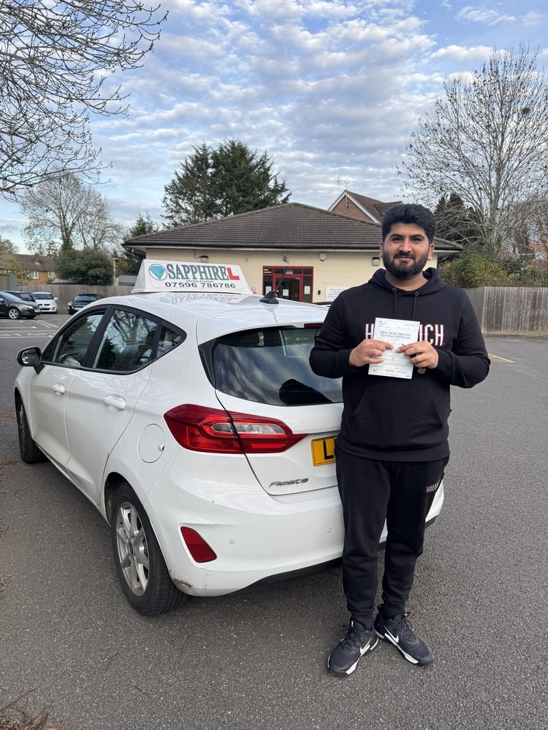 A learner standing proudly with their driving test pass certificate